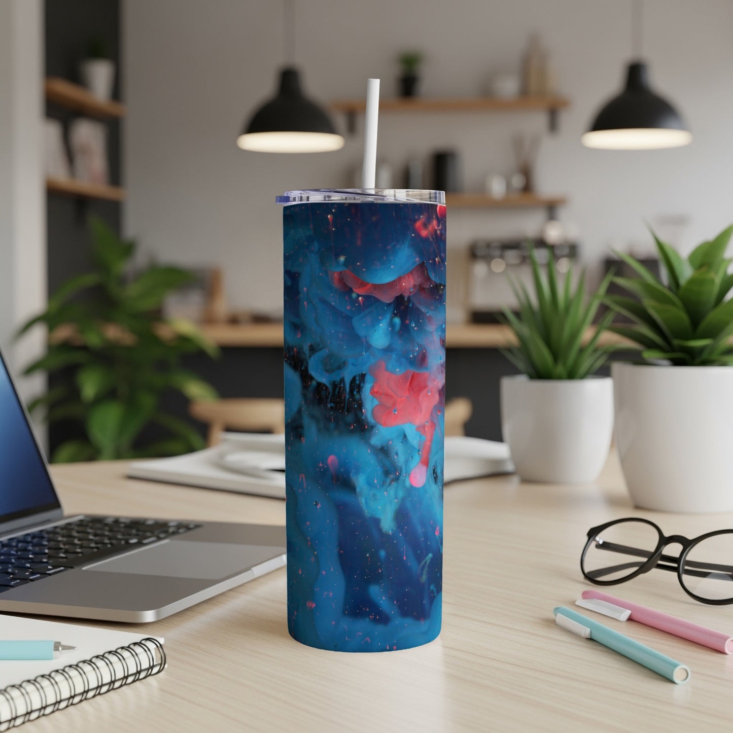 Blue and pink abstract ink design on a tall, cylindrical tumbler with a straw.