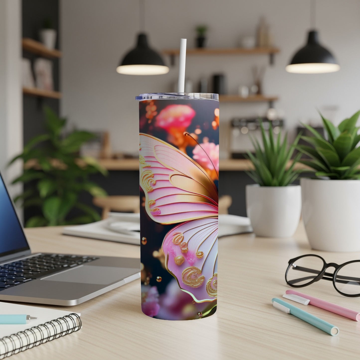 Pink and gold butterfly tumbler with straw on a desk.