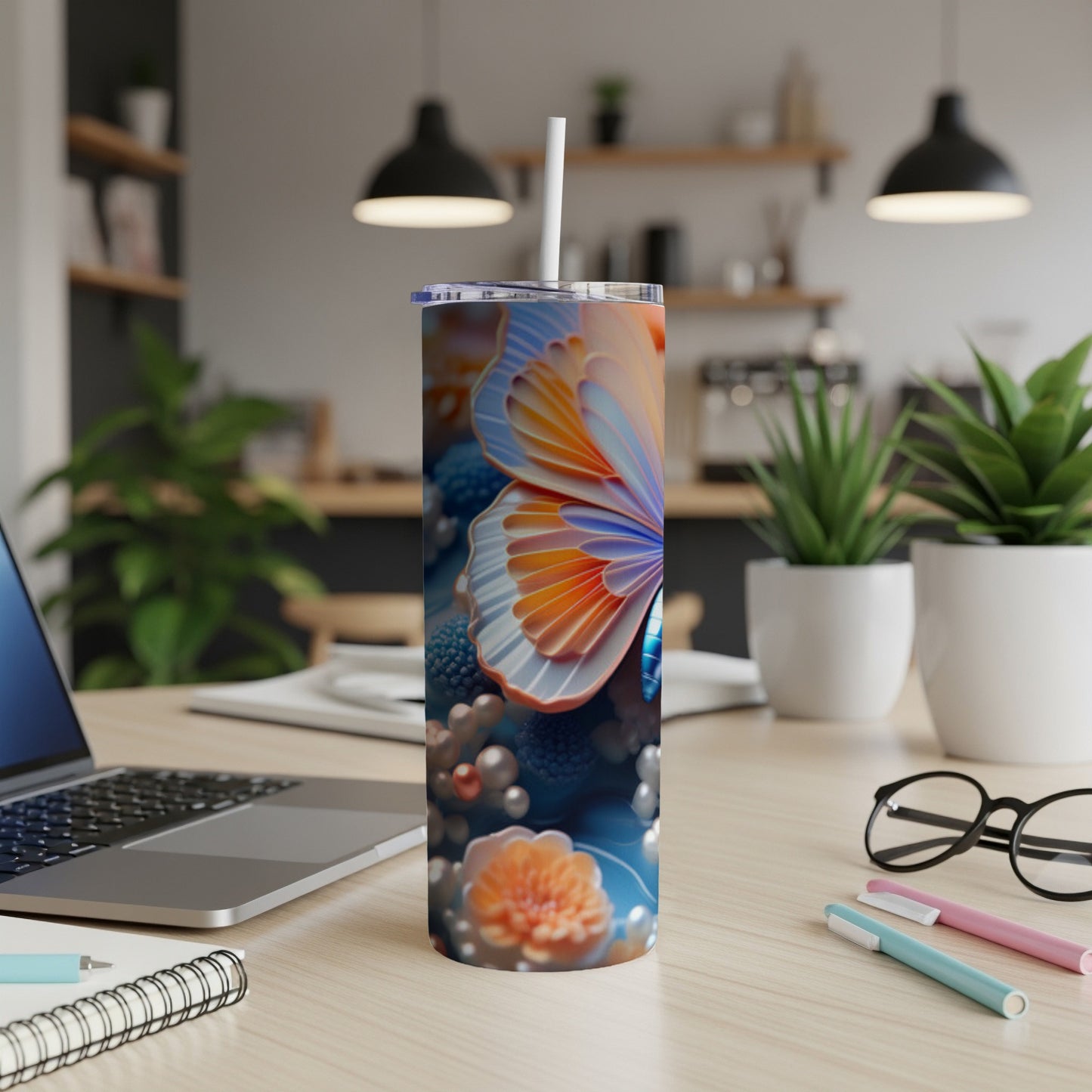 Tall tumbler with butterfly and floral design on a desk.
