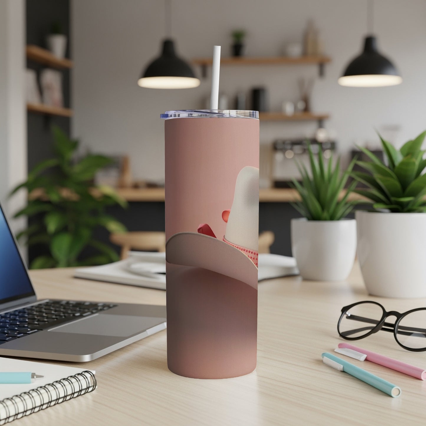 Cowboy hat tumbler with straw on a desk.