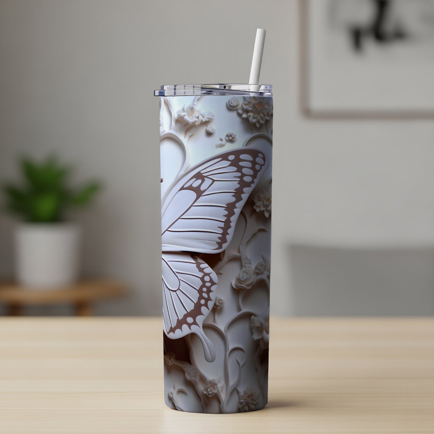 White tumbler with raised butterfly and floral relief design and straw.