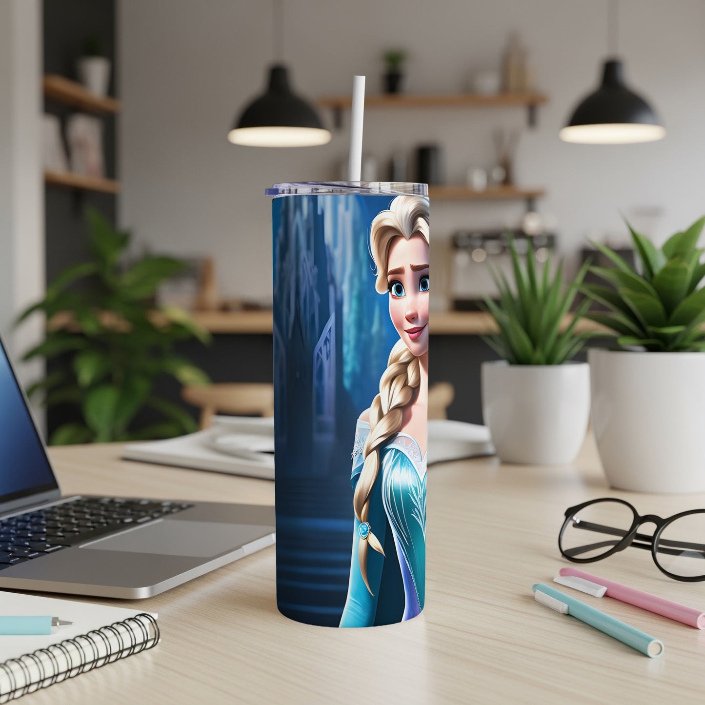 Elsa from Frozen on a blue tumbler with a white straw on a desk.