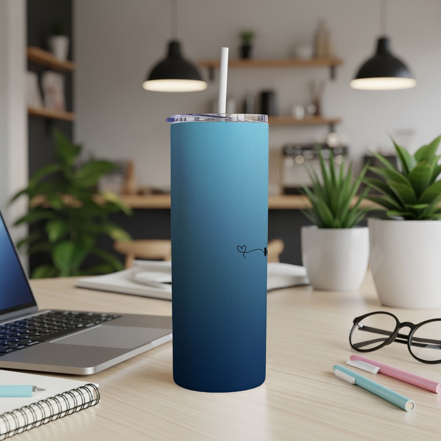 Blue gradient tumbler with heart and initial design on a desk.
