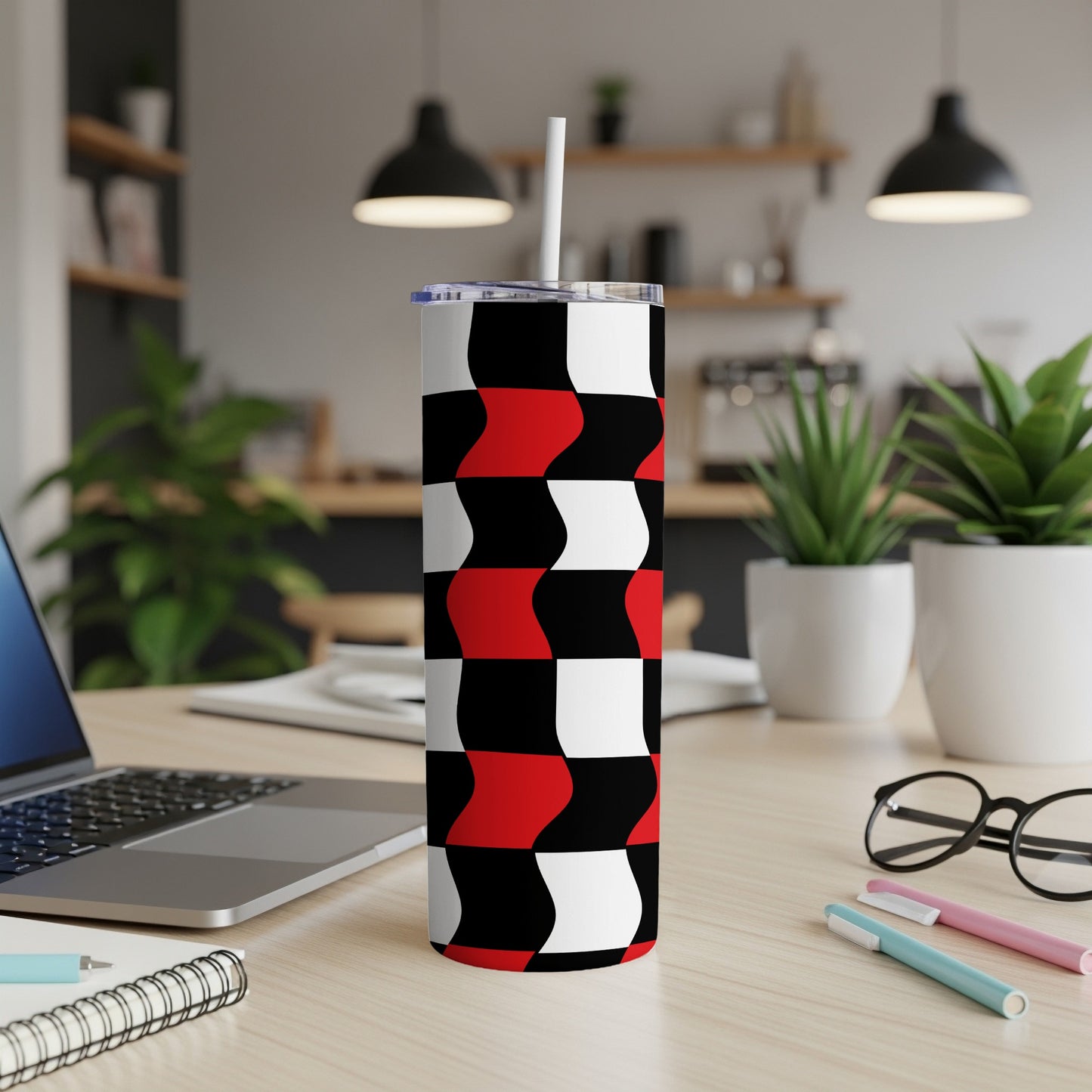 Black, white, and red wavy geometric pattern tumbler with straw on desk.