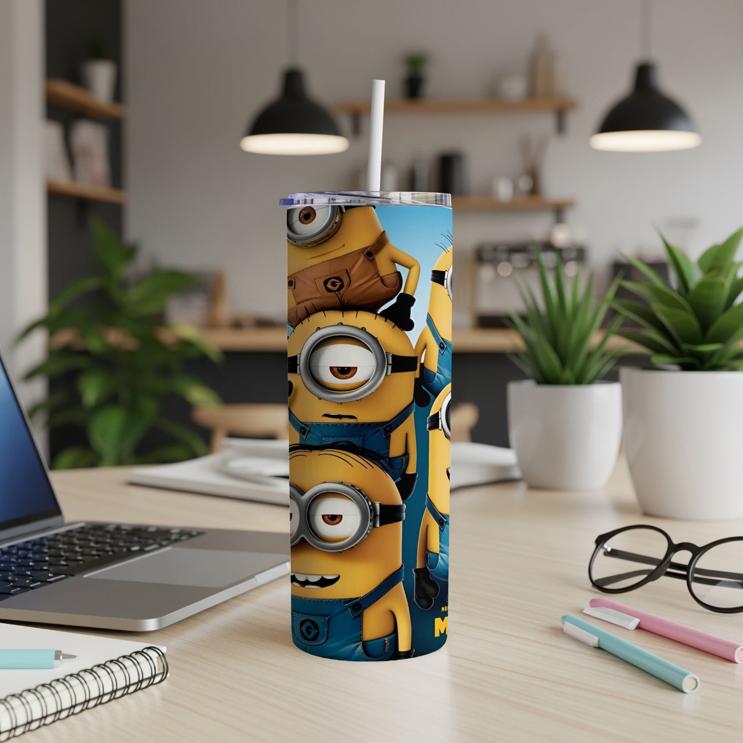 Minions on a blue tumbler with a straw, sitting on a desk.