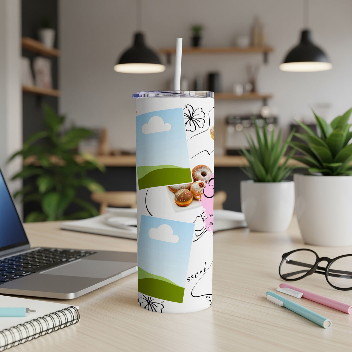 Tumbler with donuts, clouds, flowers, and text on a desk with laptop.