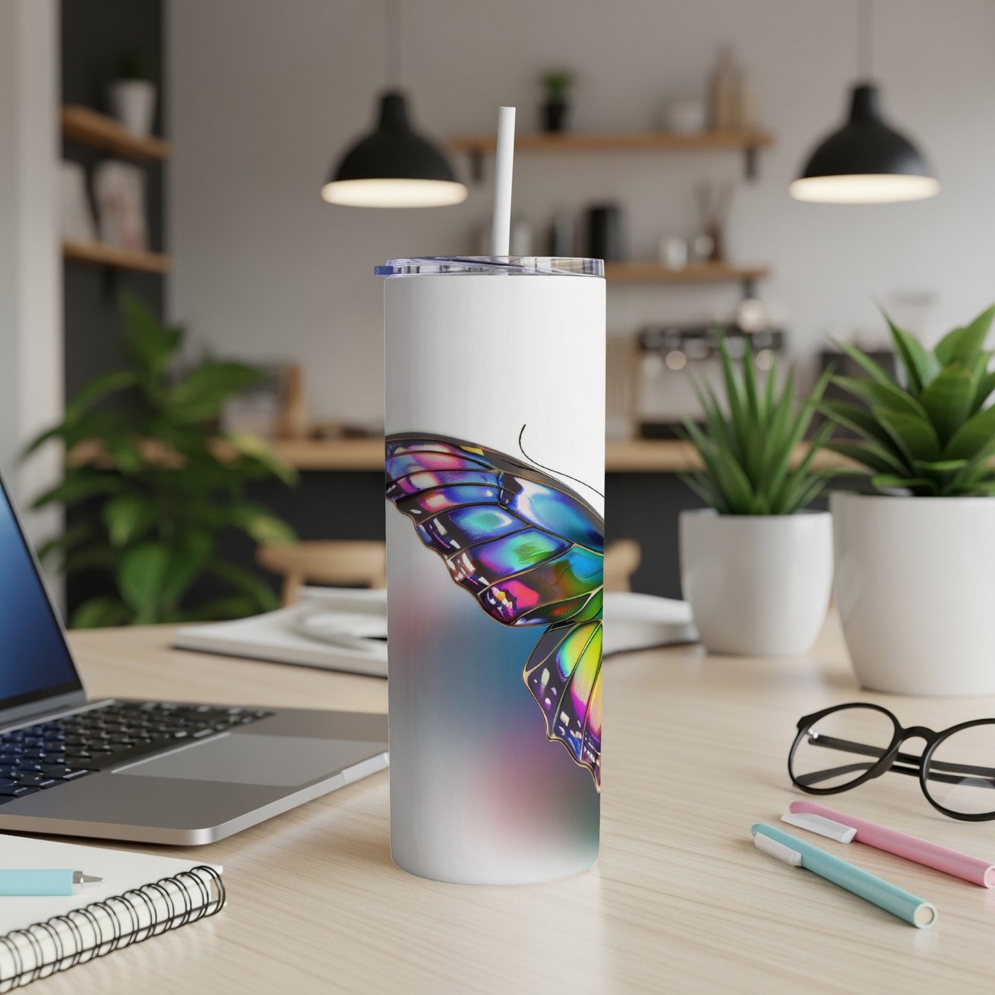 White tumbler with colorful butterfly wing design on a desk.
