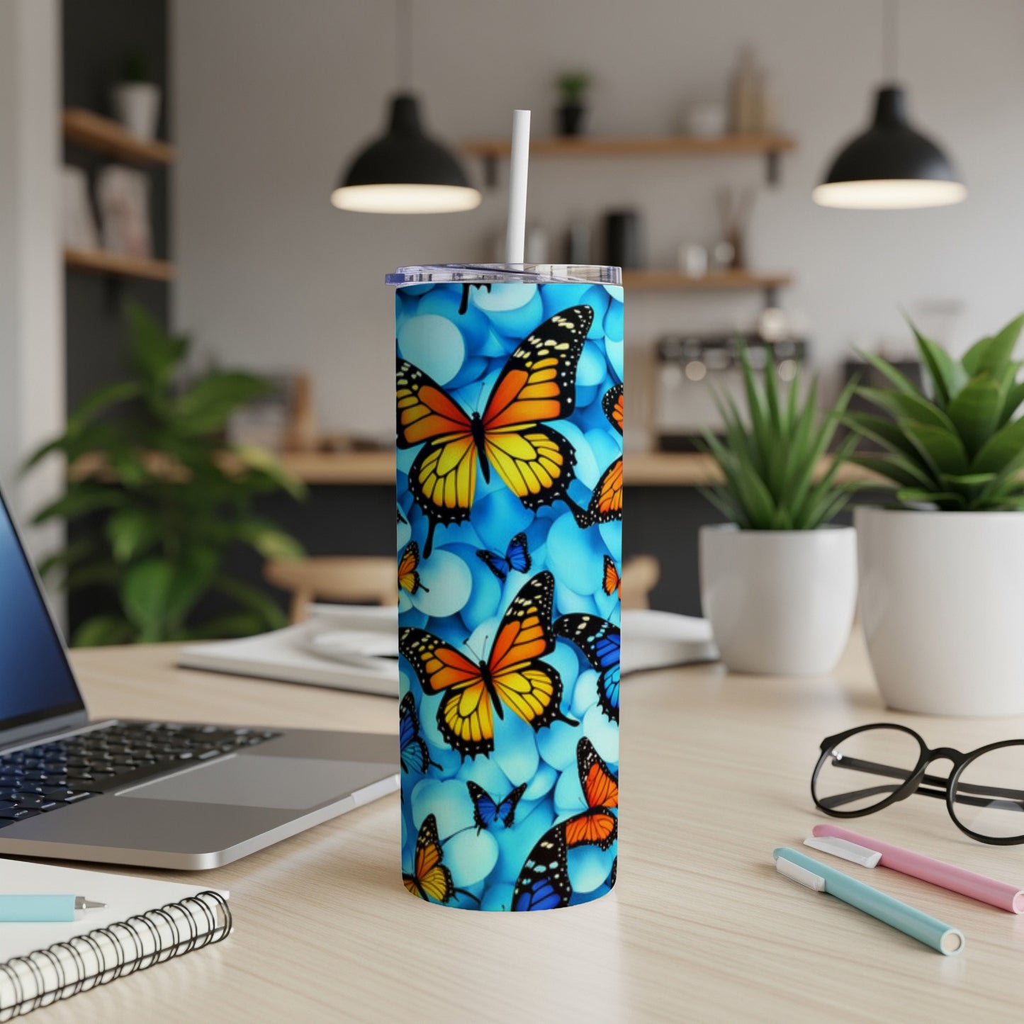 Blue tumbler with scattered colorful butterflies, resting on a desk.
