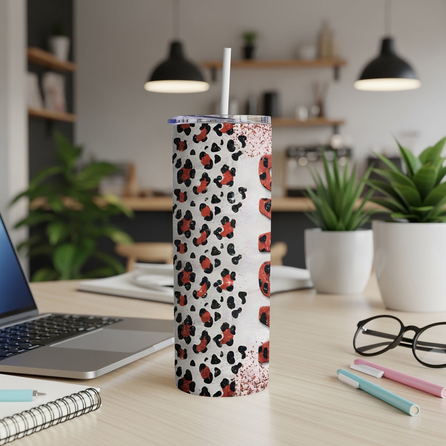 White leopard print tumbler with "mama" text, laptop, and pens on desk.