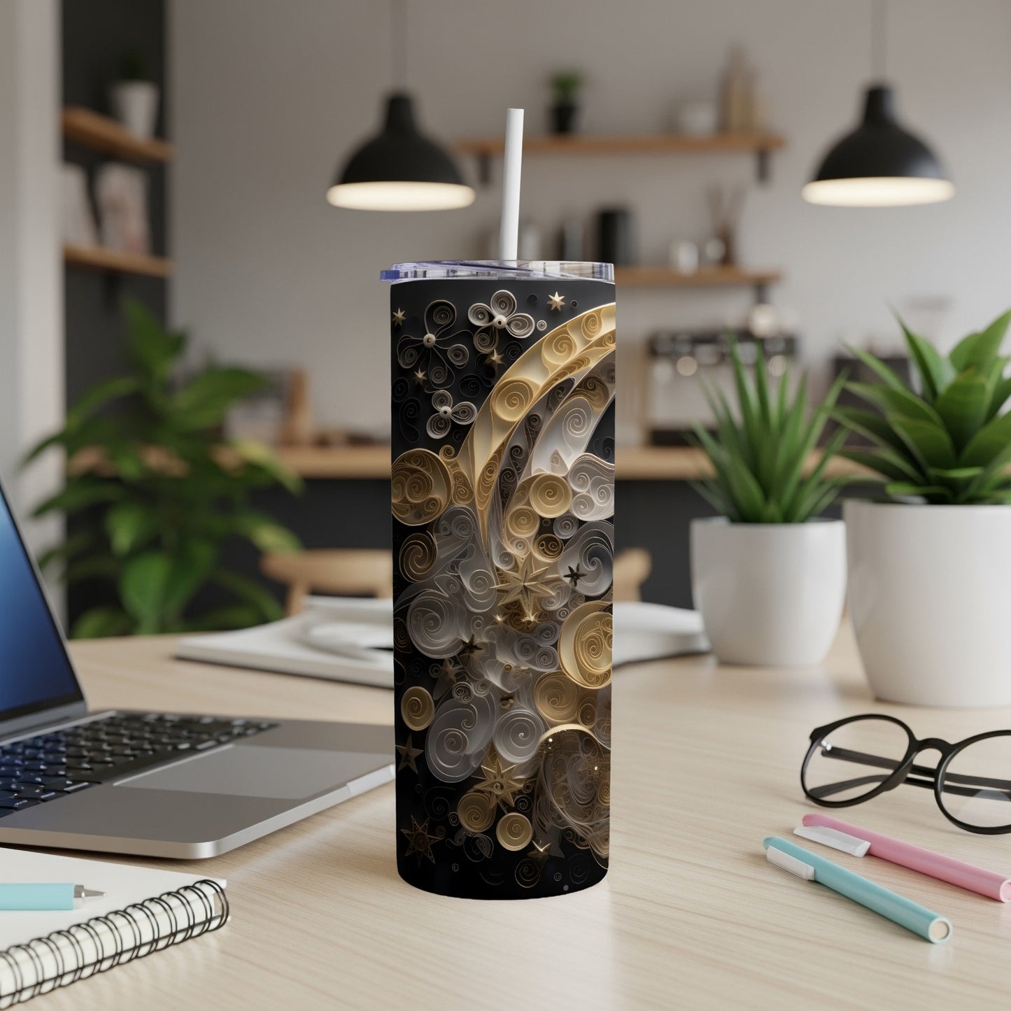 Black tumbler with gold and silver swirling decorative design and white straw.