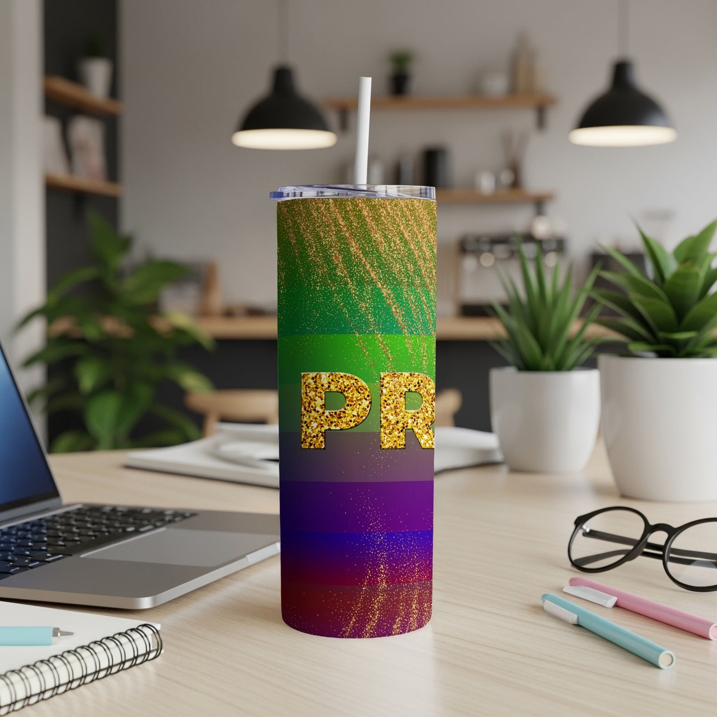 Rainbow glitter tumbler with "PR" text, on a desk with a laptop.
