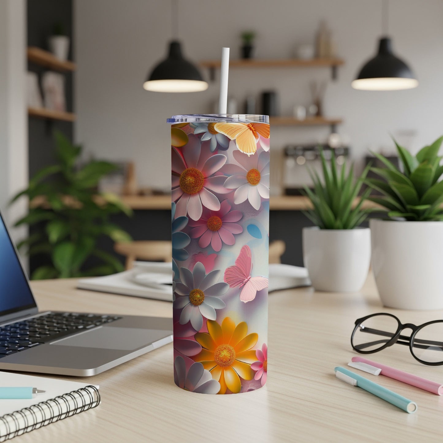 Tumbler with colorful floral and butterfly pattern on a desk.