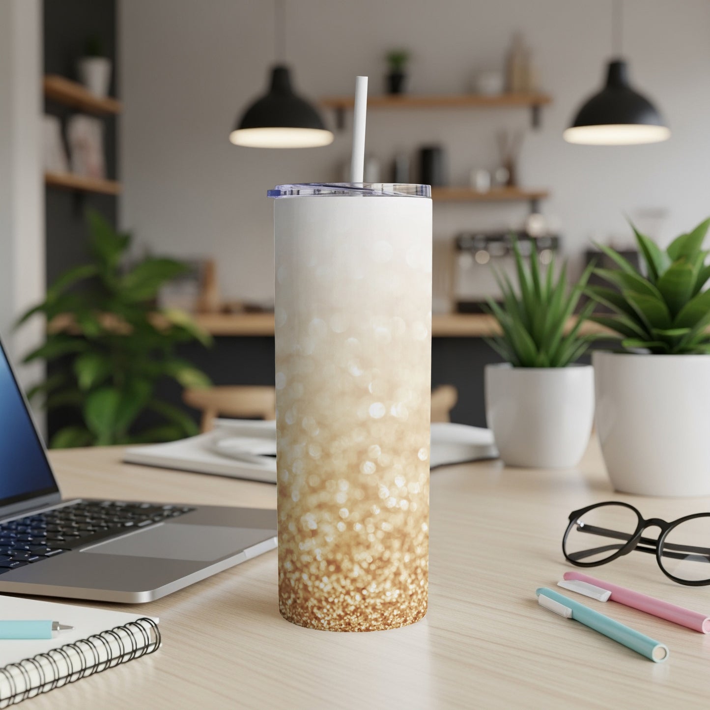 White tumbler with gold glitter design and straw on a desk.