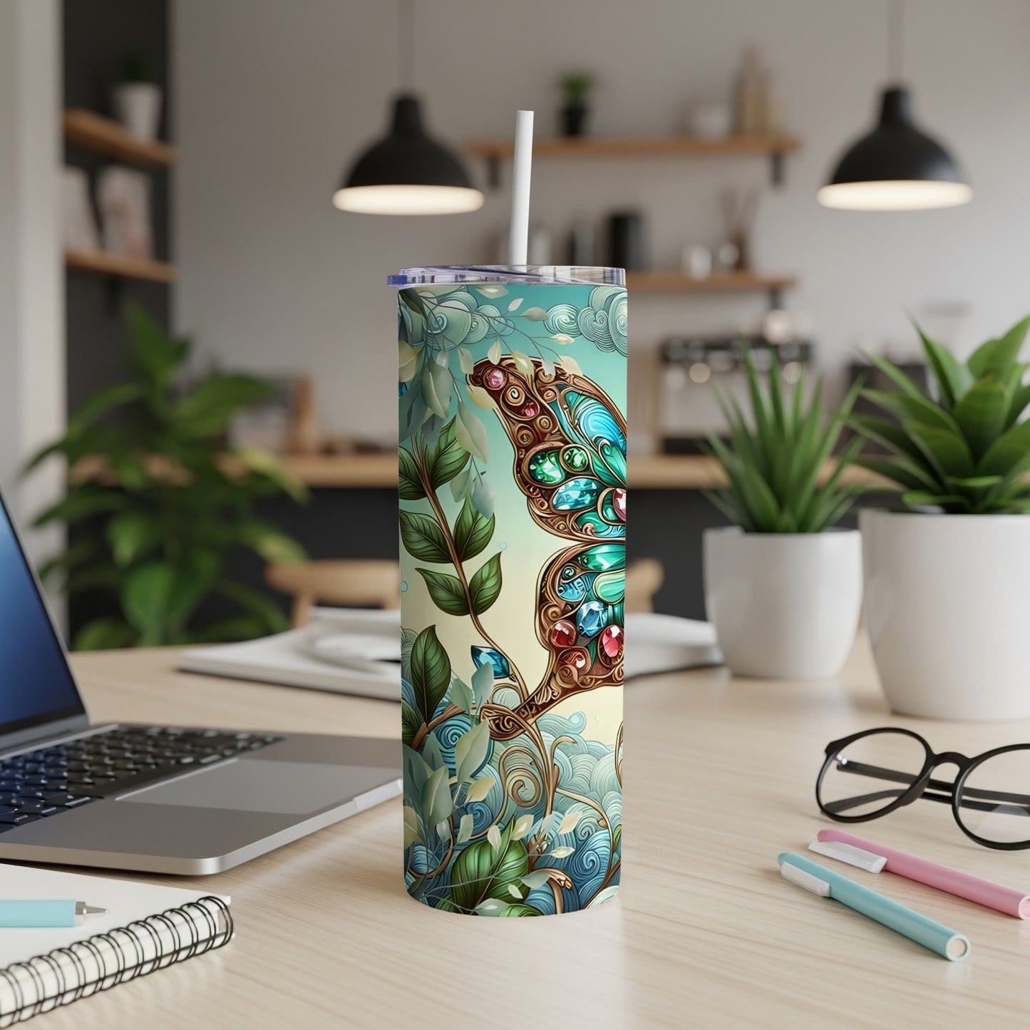 Tumbler with a jeweled butterfly and floral design on a desk.