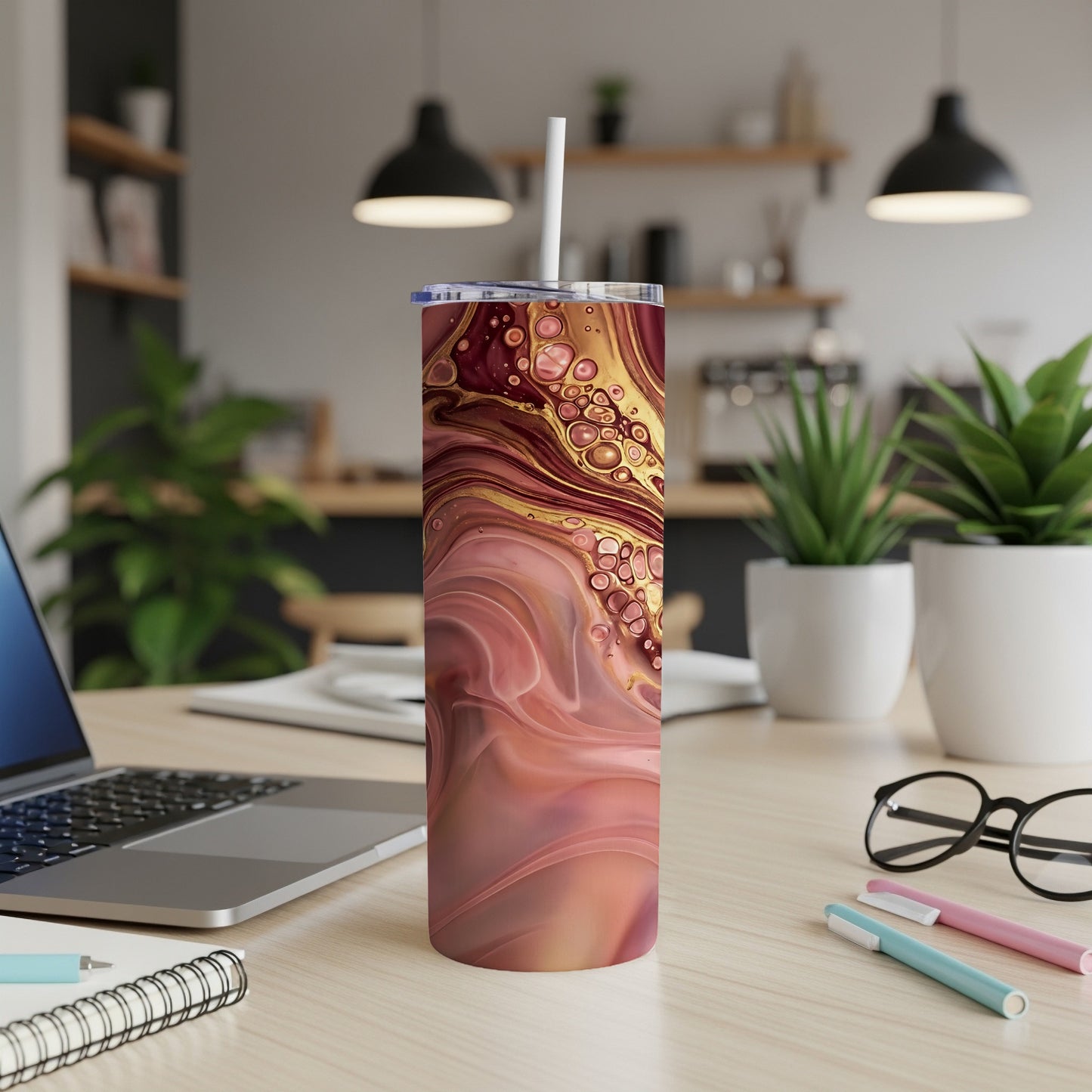 Marble pattern tumbler with straw on desk next to laptop.