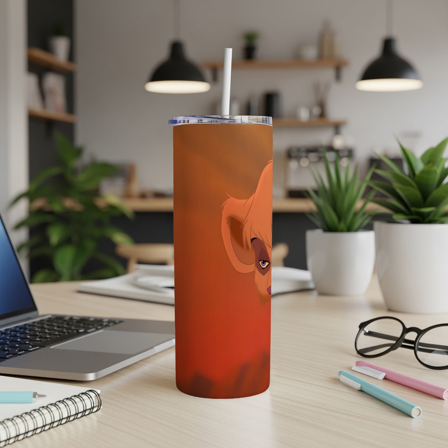 Orange tumbler with a lion cub character on a desk.