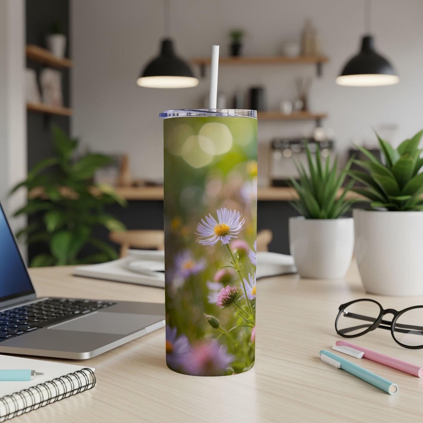 Floral patterned tumbler with straw on a desk next to a laptop.