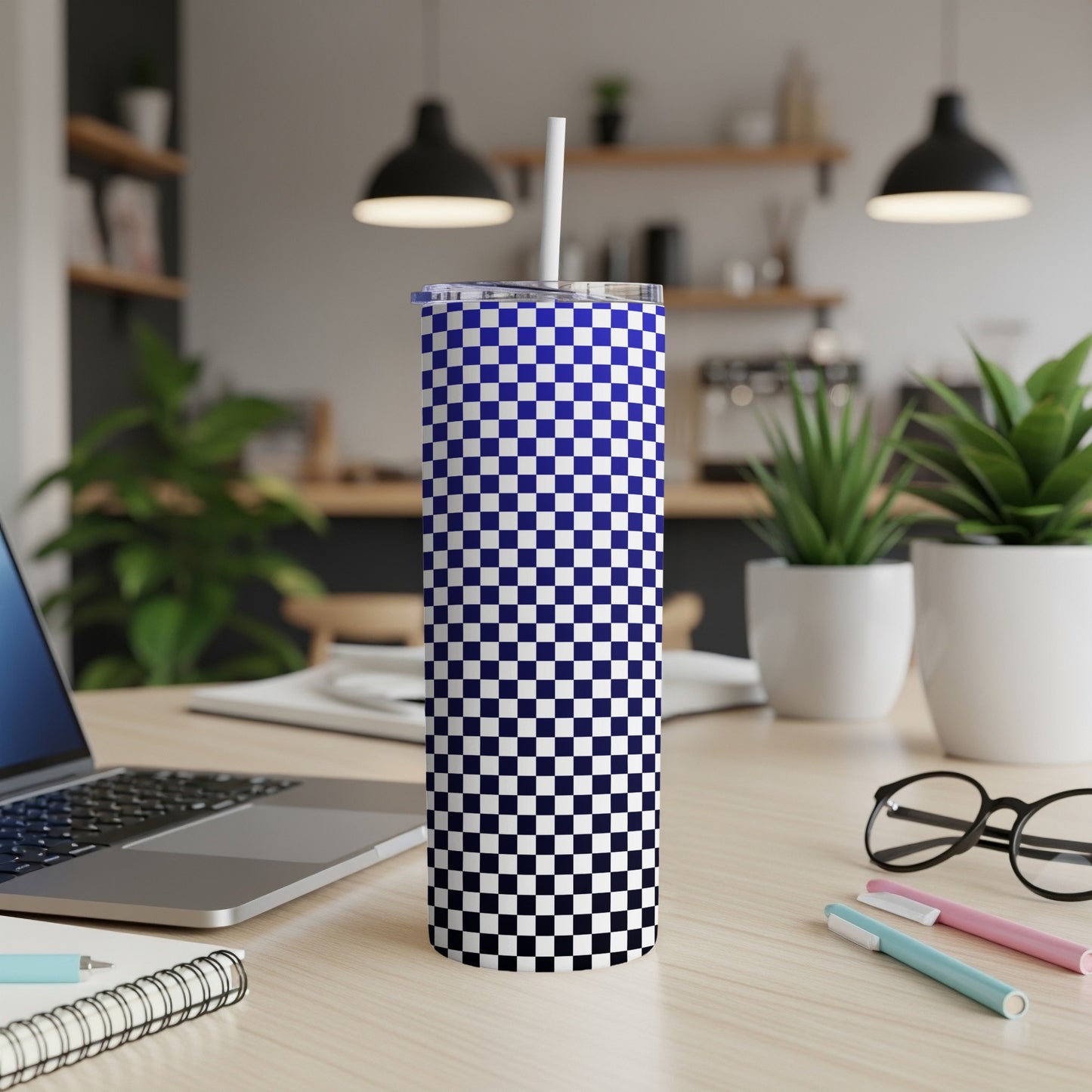 Blue and white checkered tumbler with straw on a desk.