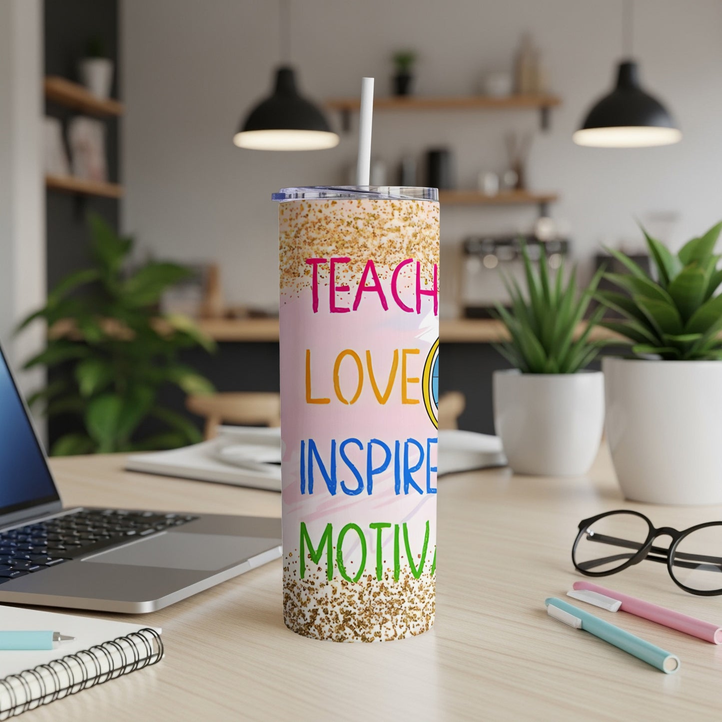 "Teach love inspire motivate" tumbler with a straw on a desk.