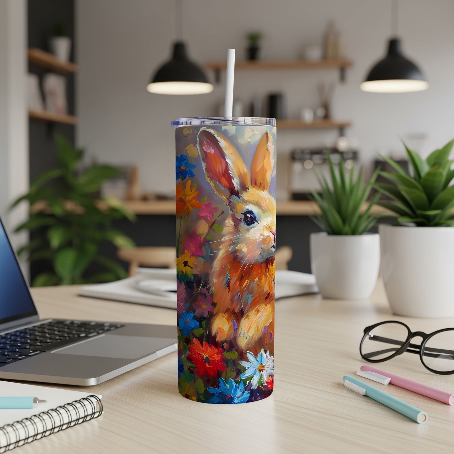 Bunny illustration on a colorful floral tumbler with straw on a desk.