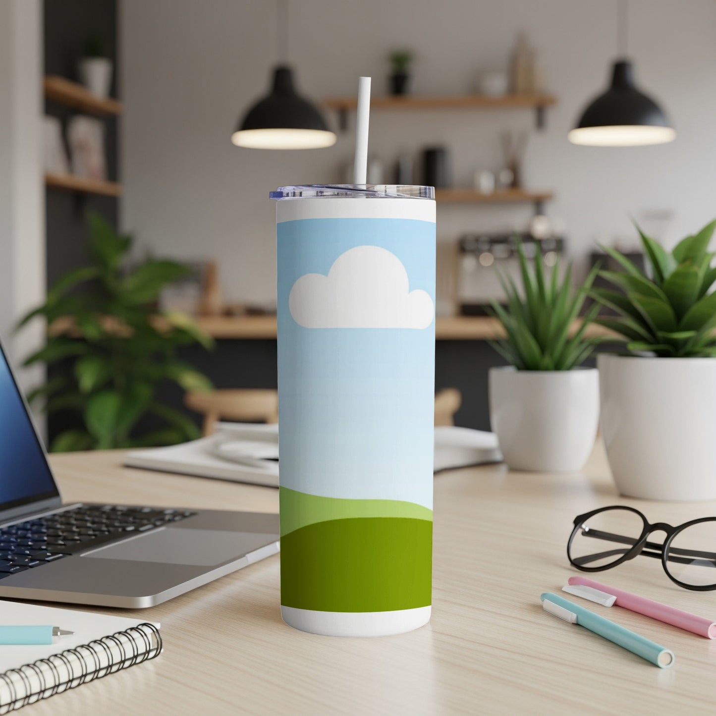 Tall tumbler with a sky and green hills design and a straw.