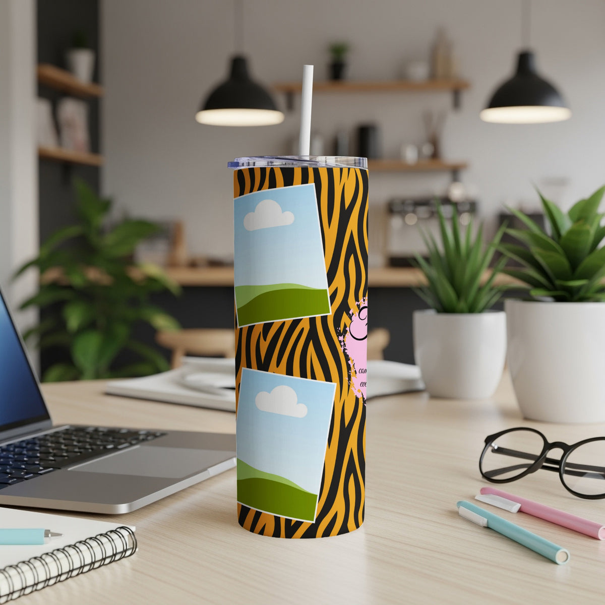 Tumbler with tiger stripe pattern and framed images on a desk.