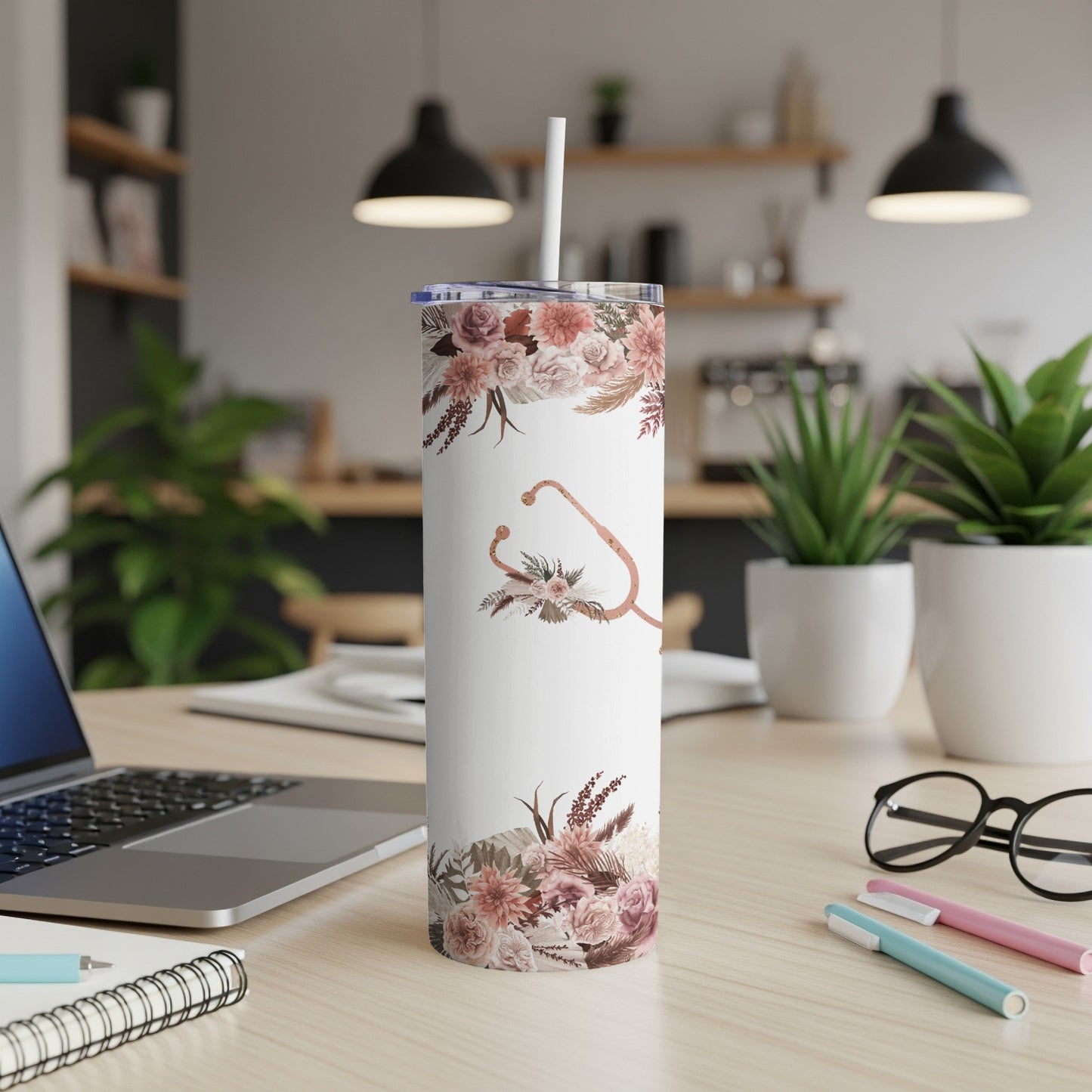 White tumbler with floral pattern and stethoscope, straw inserted.