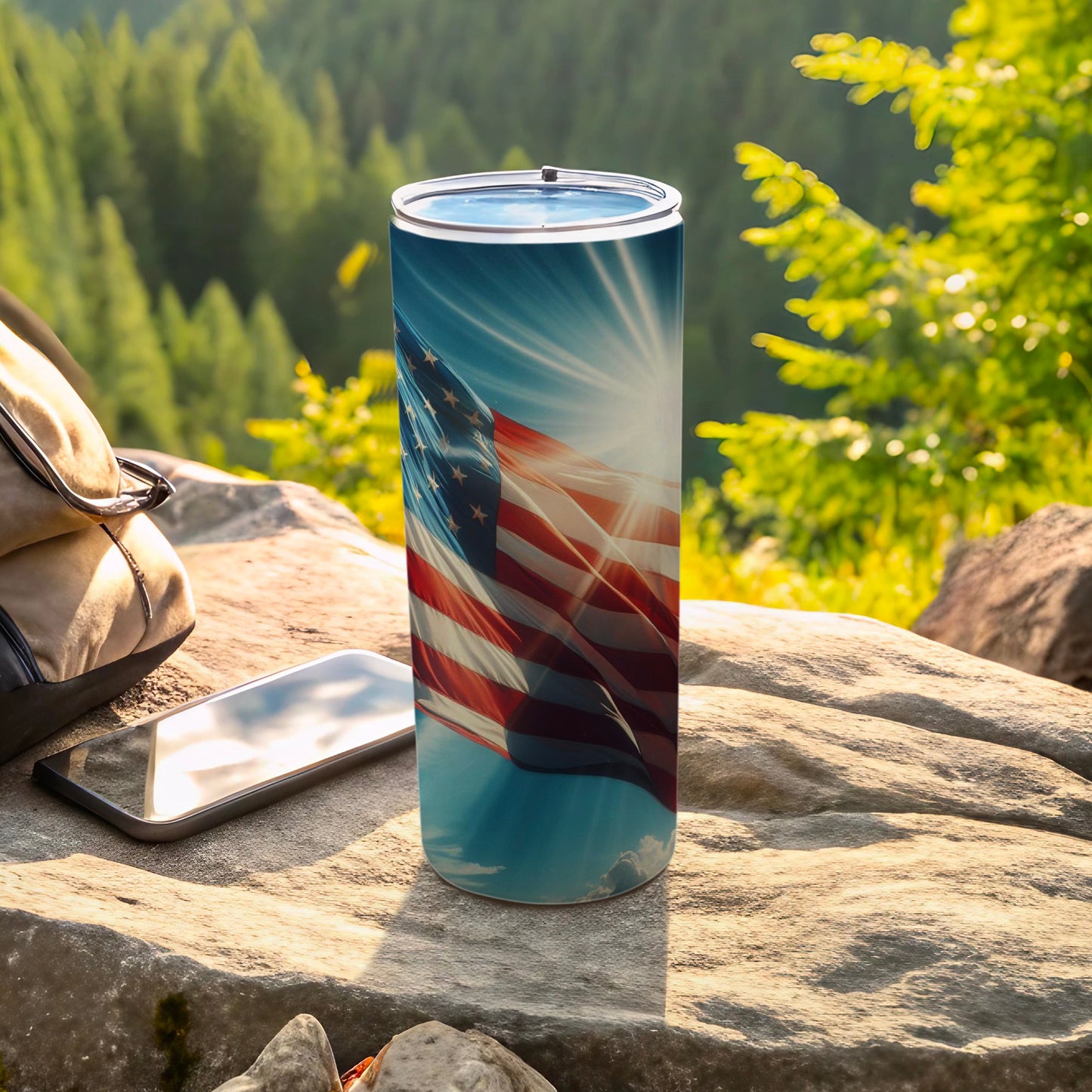 American flag tumbler with sun flare, backpack, and phone on rocks.