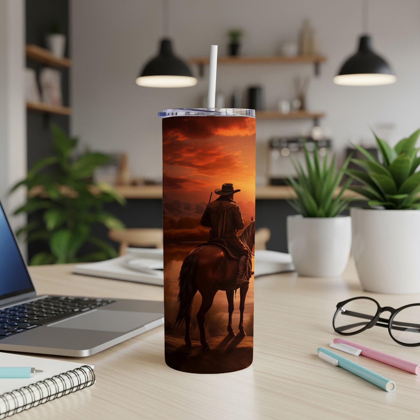 Cowboy on horseback against a sunset sky, beside a body of water.