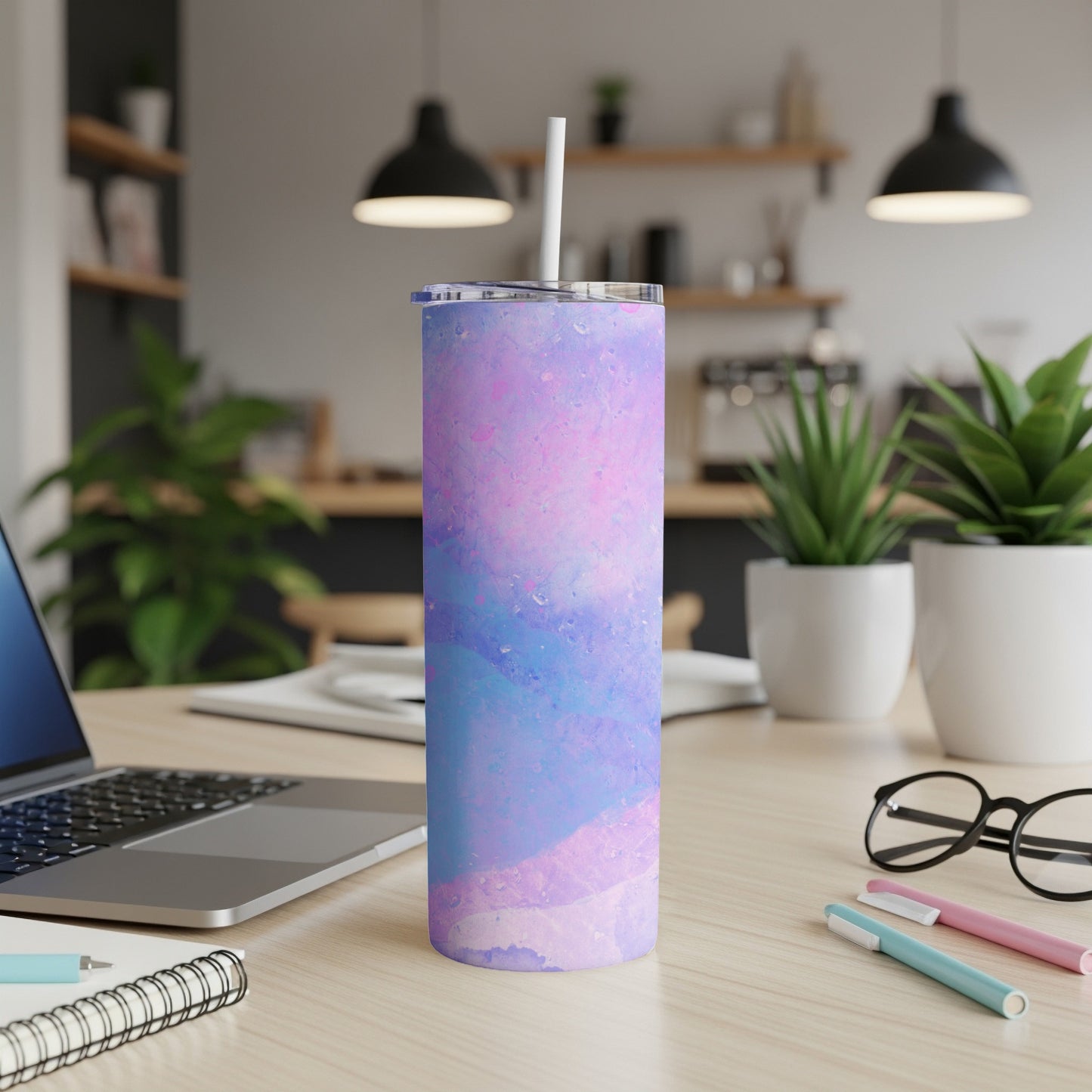 Tall tumbler with marbled pink and blue design on desk with laptop and pens.