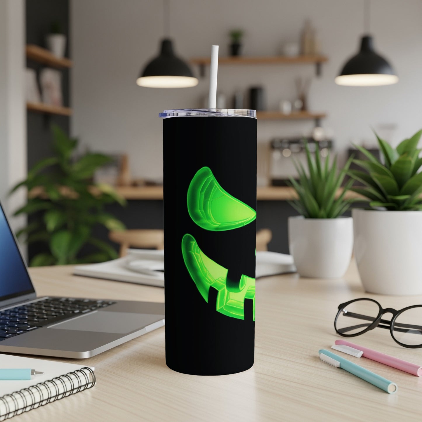 Black tumbler with neon green jack-o'-lantern face and white straw.