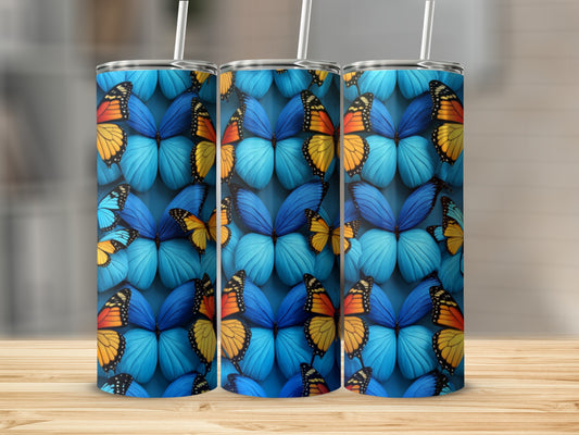 Three blue tumblers with a vibrant butterfly pattern on a wooden surface.