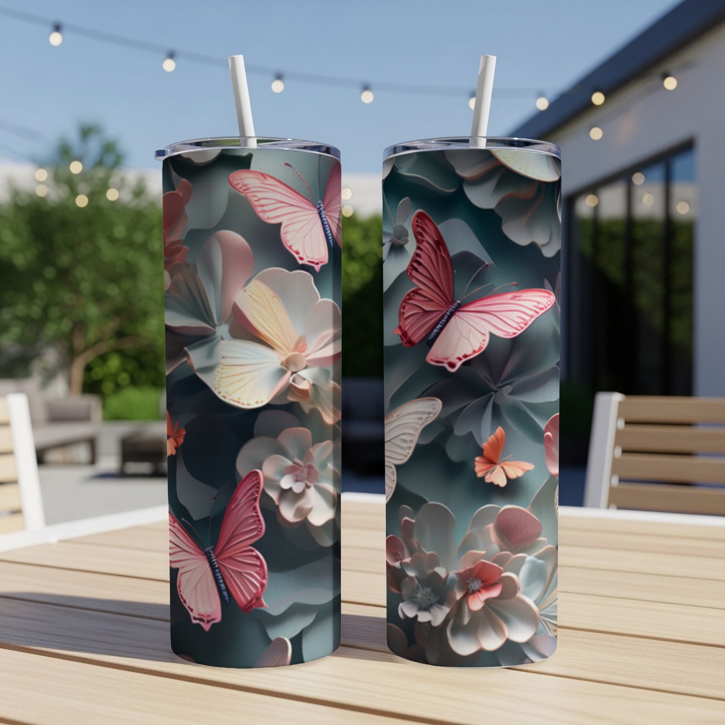 Two tall tumblers with pink butterflies and floral designs on an outdoor table.