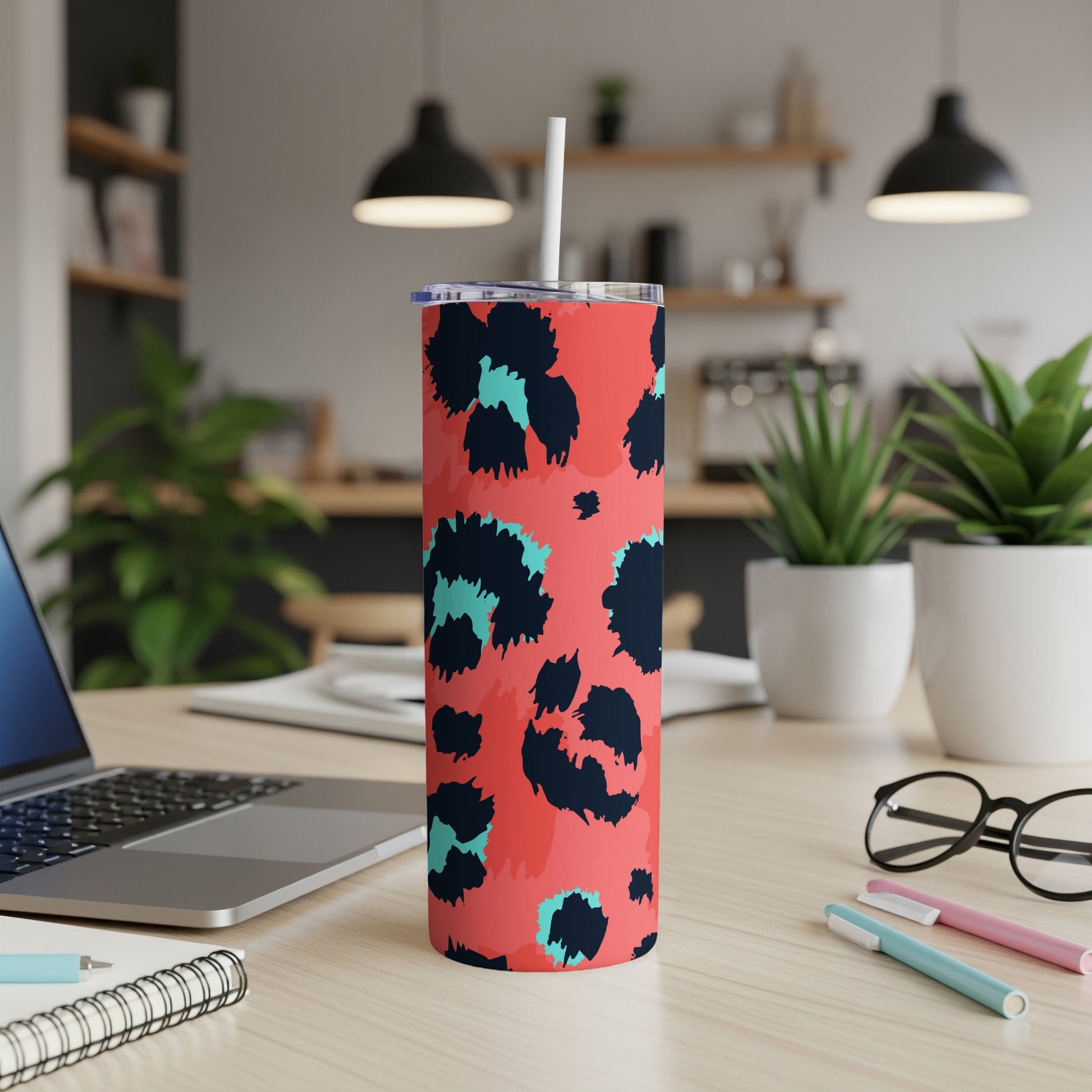 Coral tumbler with black and teal abstract spots and straw.