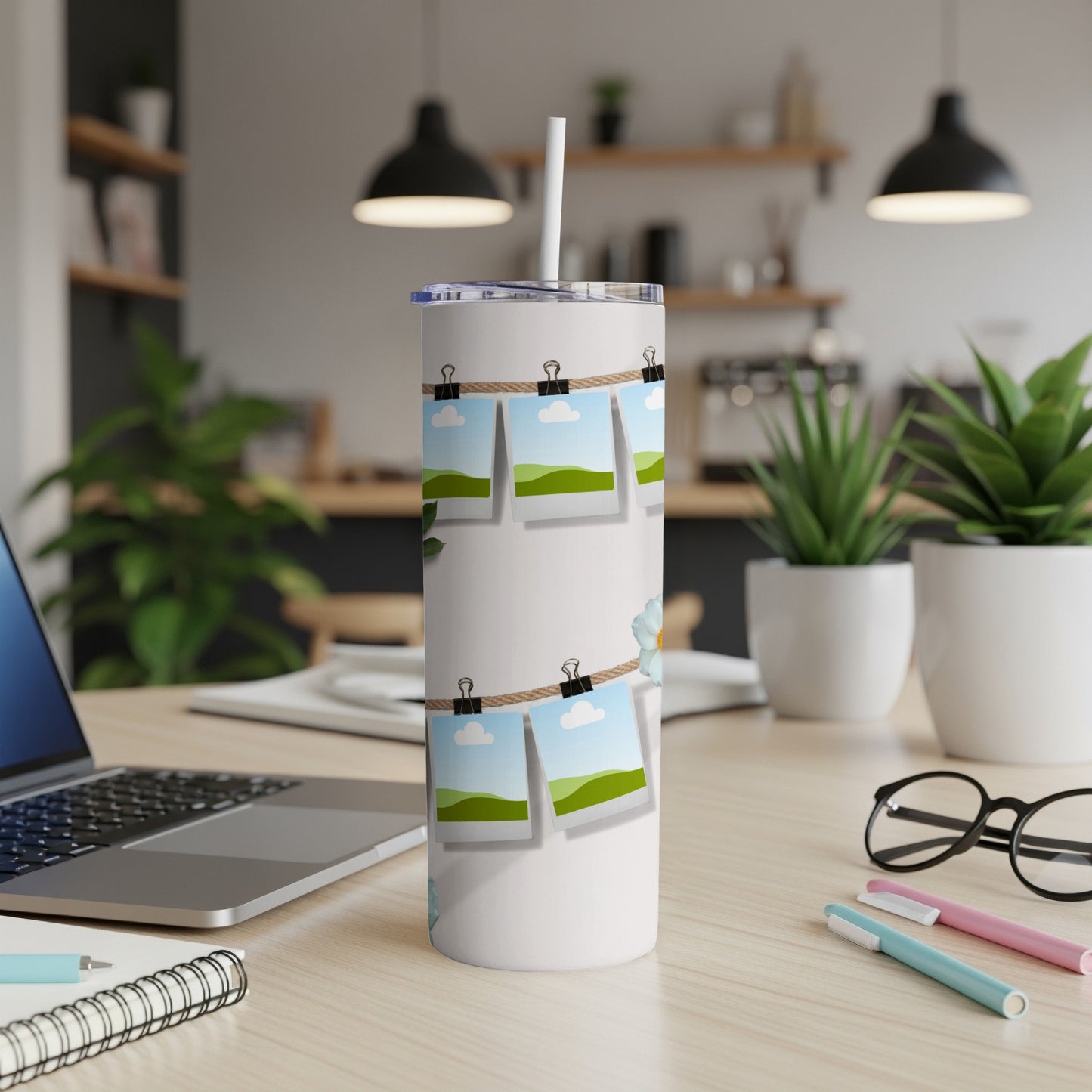 White tumbler with faux instant photos of landscapes clipped to twine.