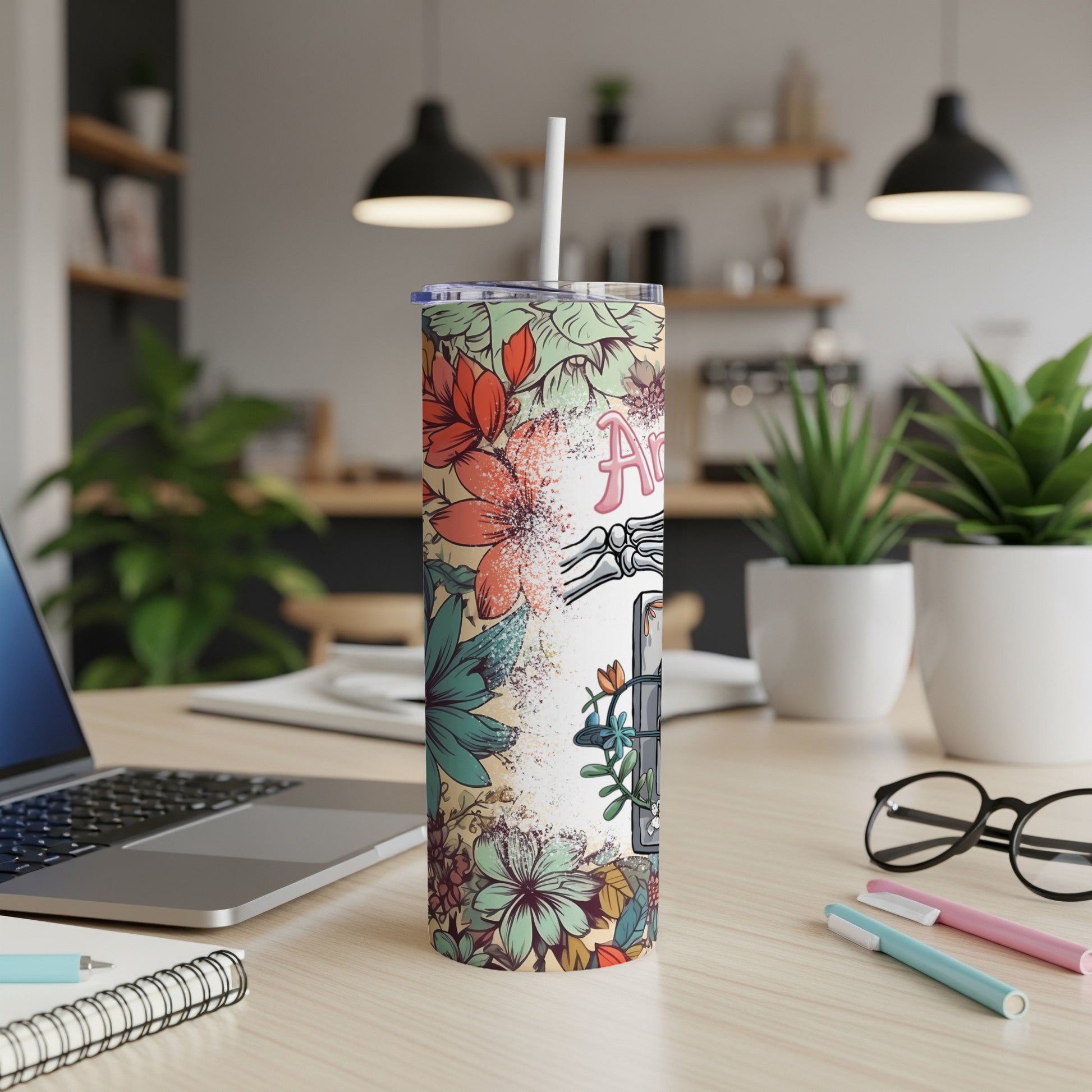 Floral tumbler with "Art" text and a straw on a desk.
