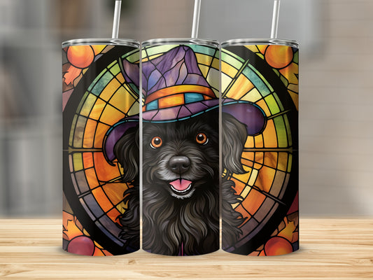 Black dog wearing a witch hat with stained glass fall leaves background.