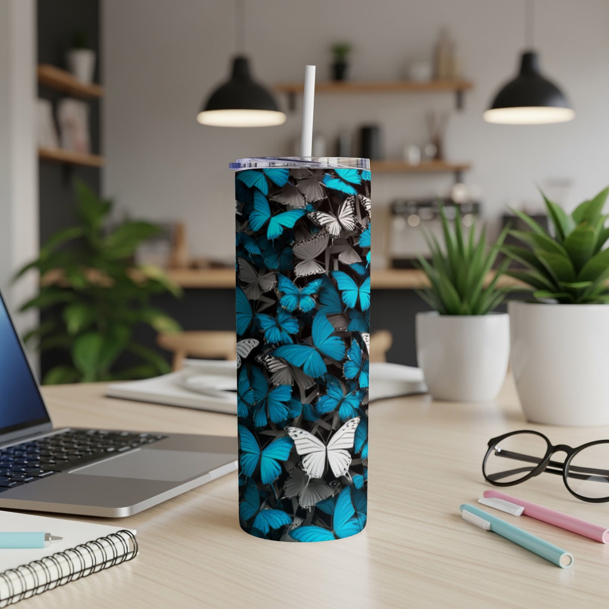 Tall tumbler with blue and gray butterflies on a desk.