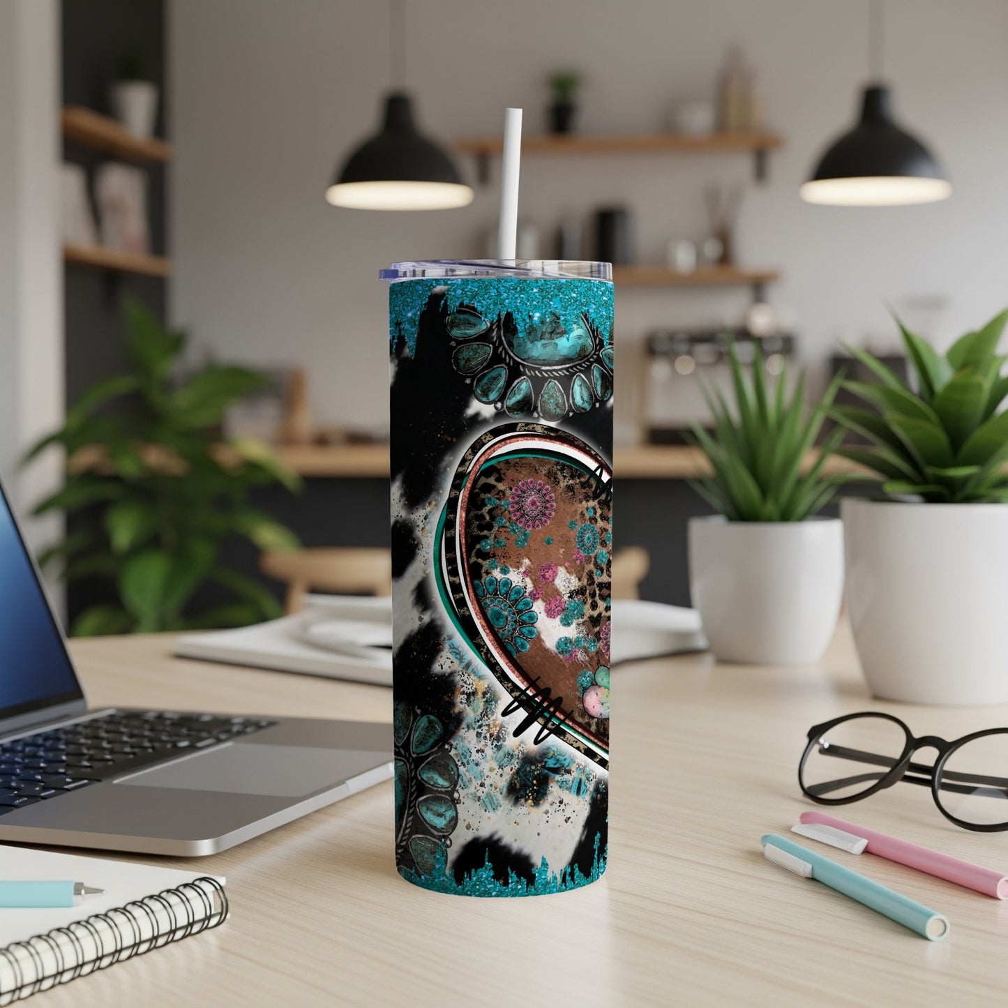 Cowhide and floral heart tumbler with turquoise accents on a desk.