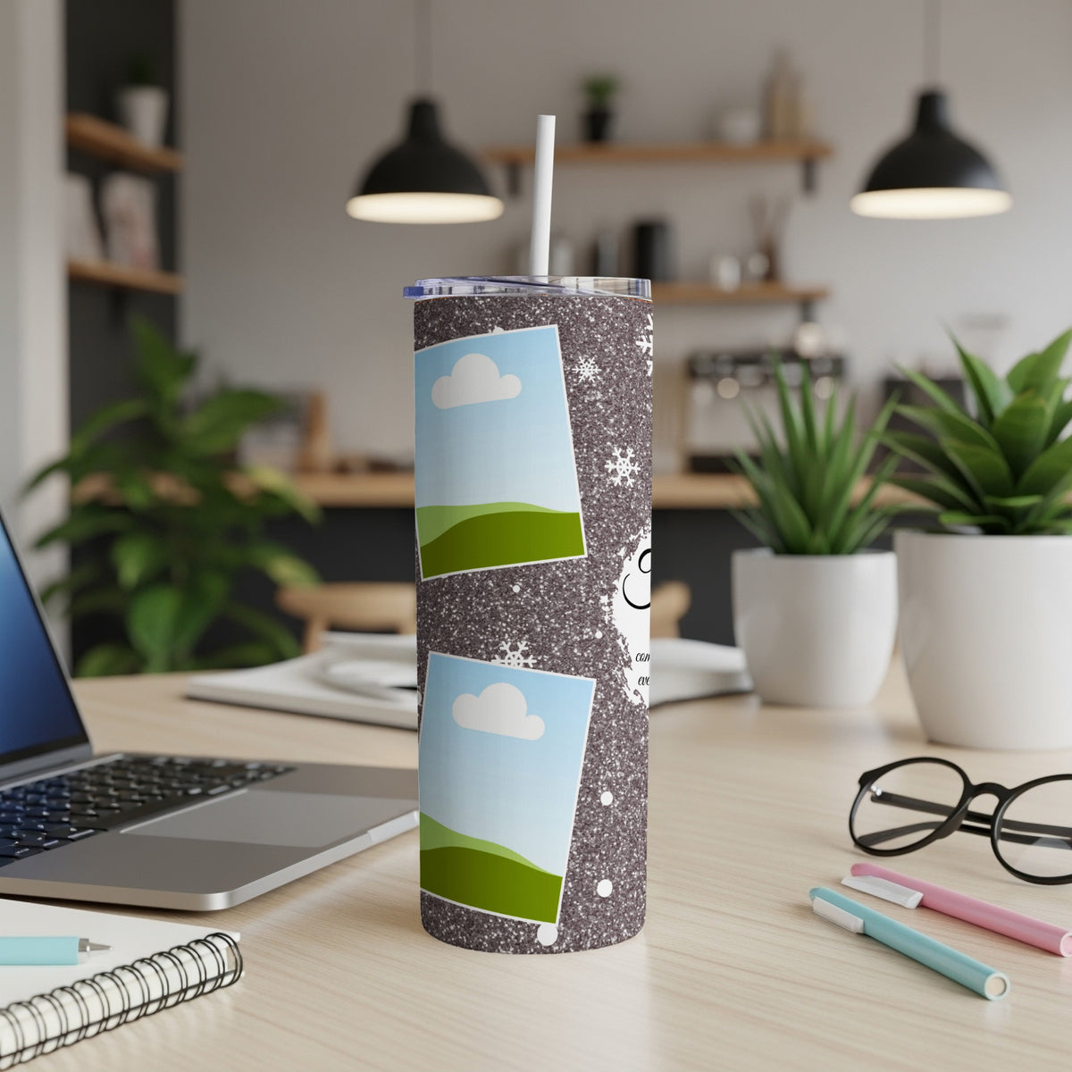 Sparkly tumbler with two photo frames, snowflakes, and text on a desk.