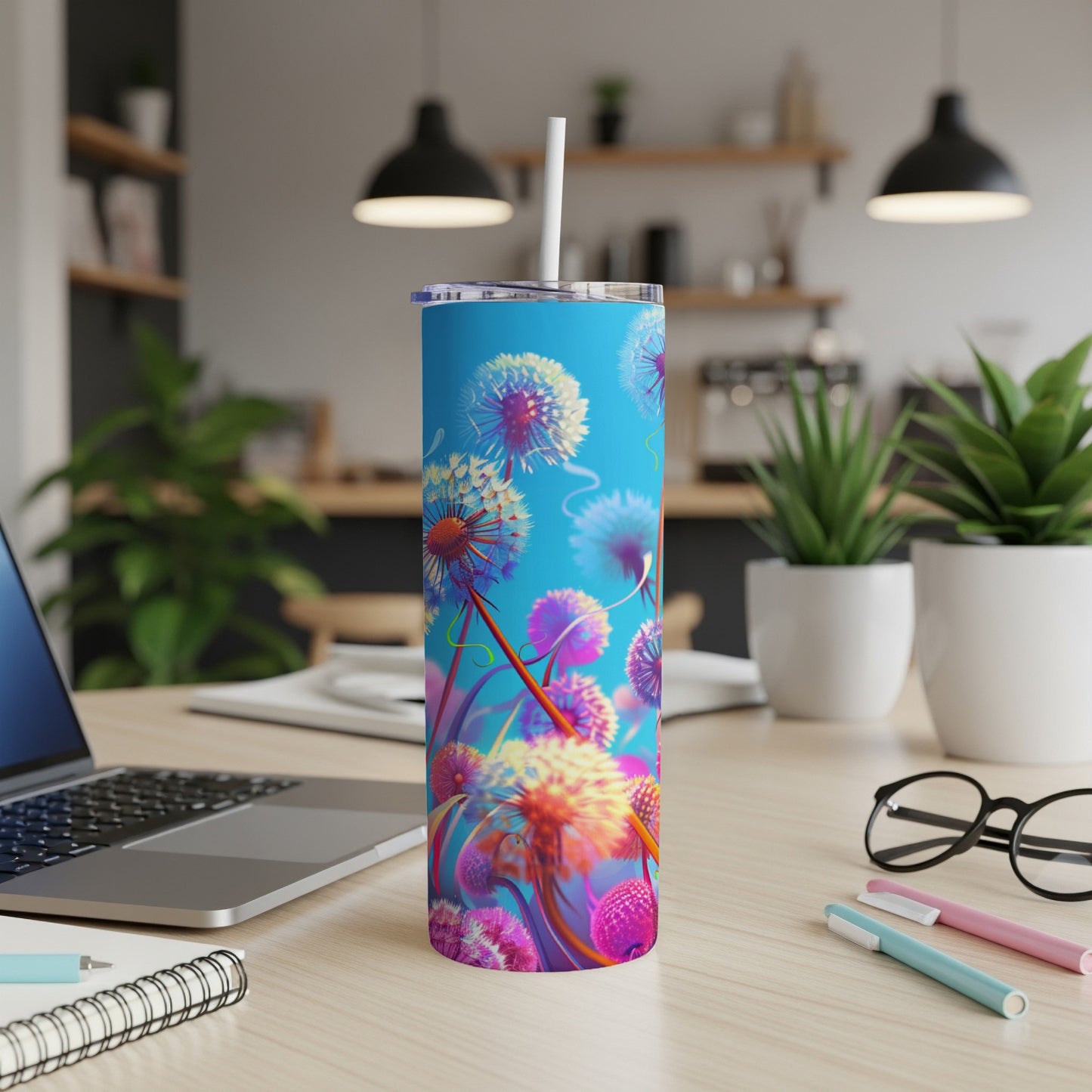 Blue tumbler with dandelion design and straw on a desk.