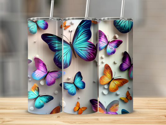Three tumblers with vibrant butterfly designs displayed on a wooden surface.