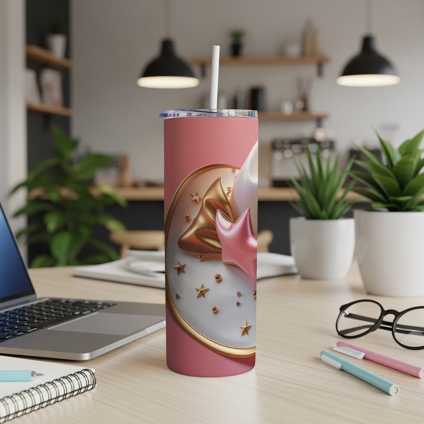 Pink tumbler with stars and moon design on a desk.