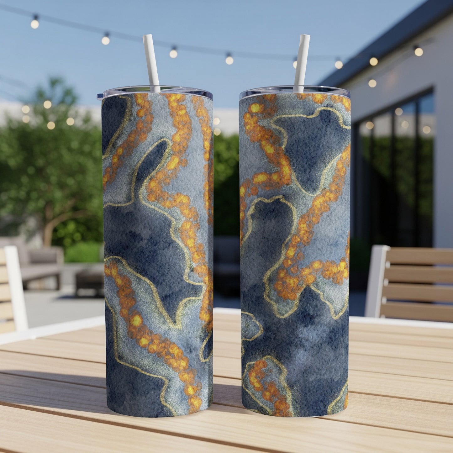 Two blue tumblers with marbled gold and orange design on a wooden table.