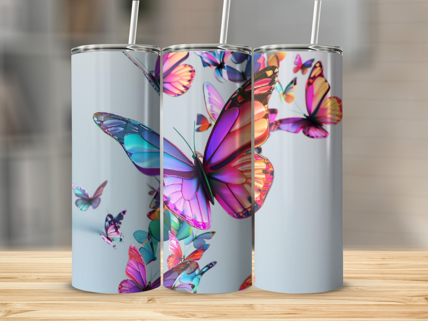 Three tumblers with colorful butterfly designs arranged on a wooden surface.
