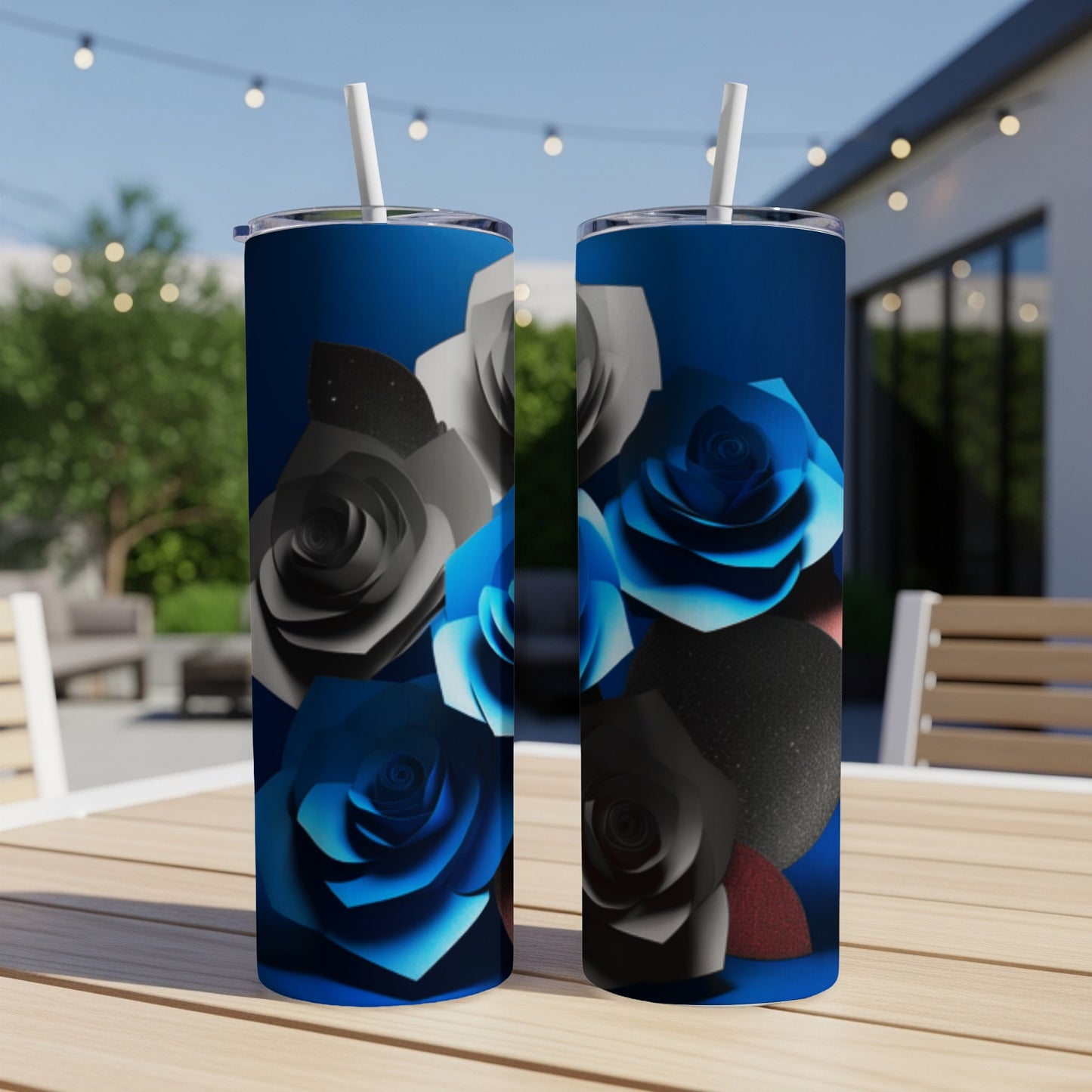 Two blue and black rose patterned tumblers with straws on a table.