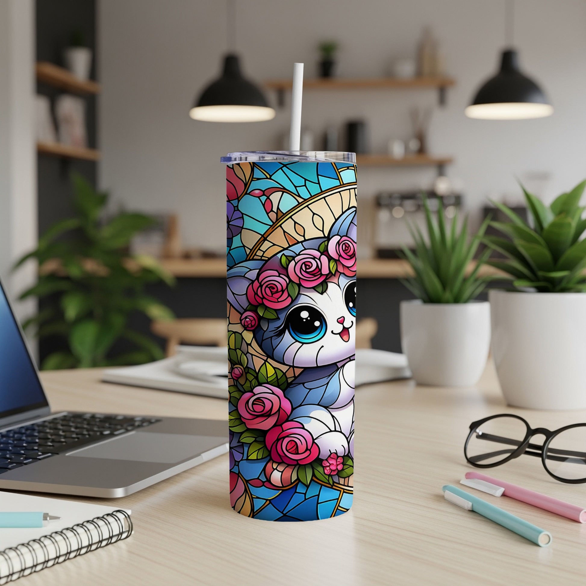 Stained glass style cat with flowers on a tumbler, with laptop and pens in background.