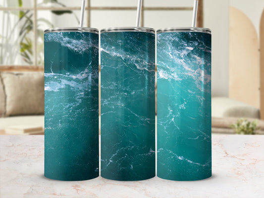 Three tumblers with a blue ocean wave design on a marbled surface.