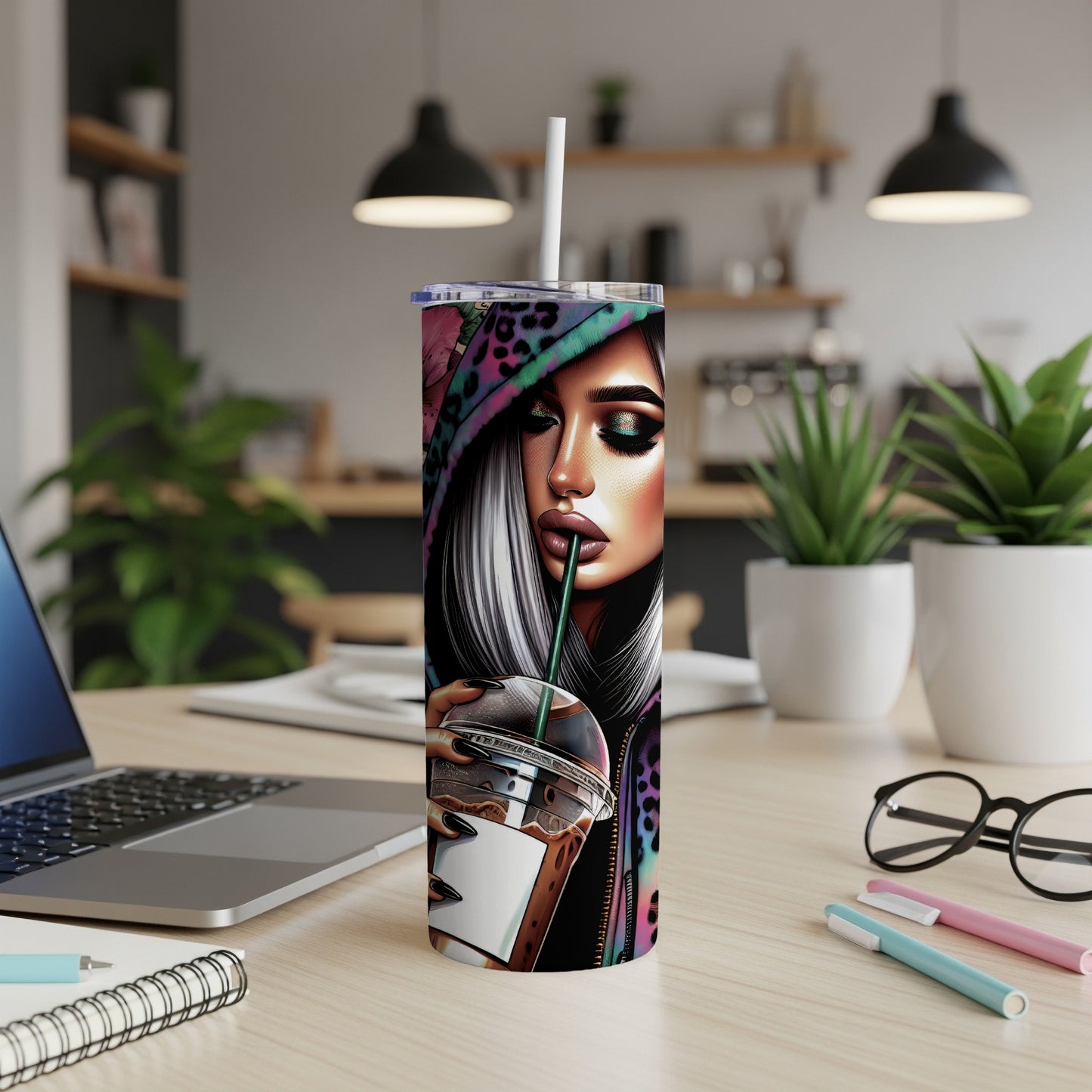 Woman with colorful makeup and hoodie drinks from a tumbler on a desk.