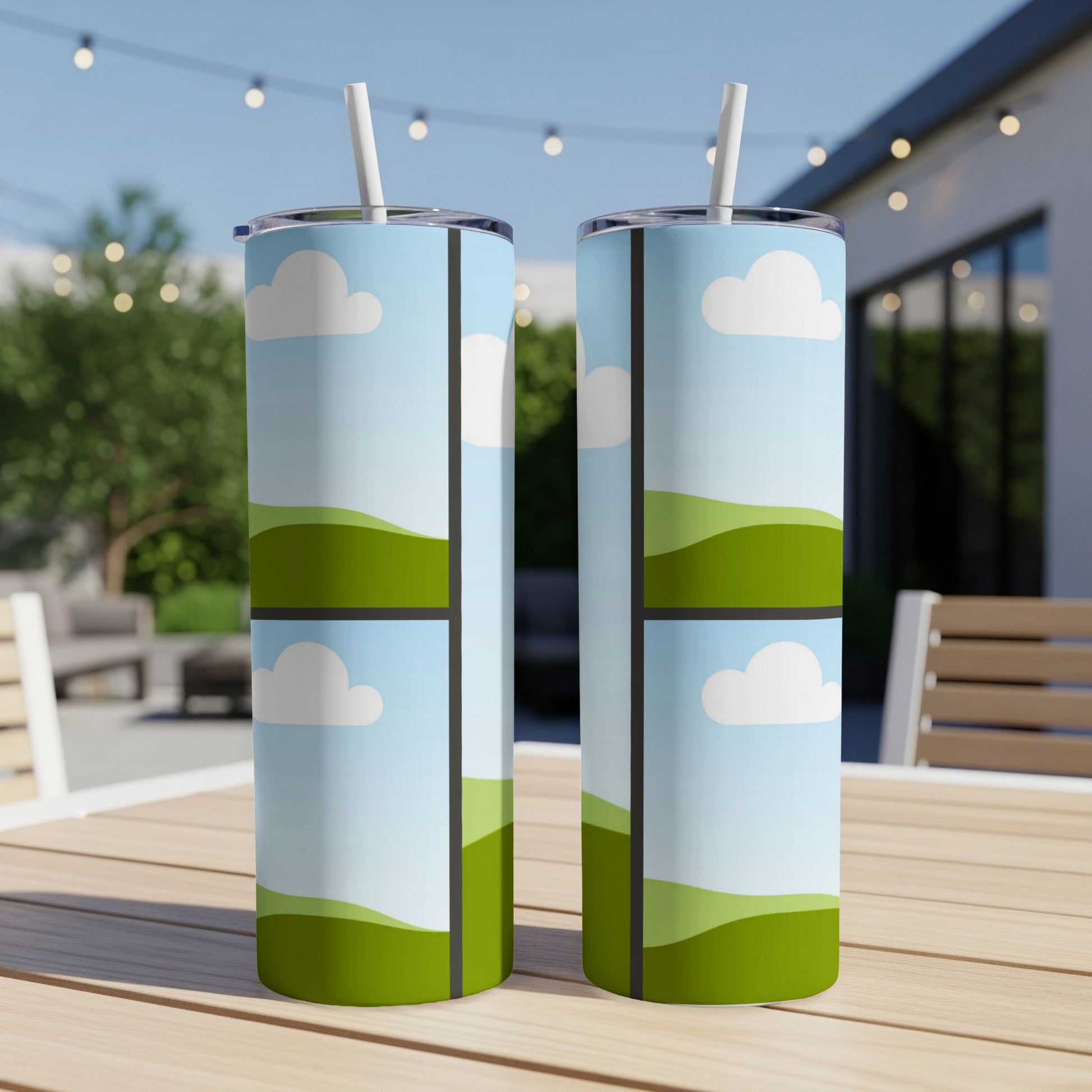 Two tumblers with a sky and rolling green hills pattern sit on a wooden table.